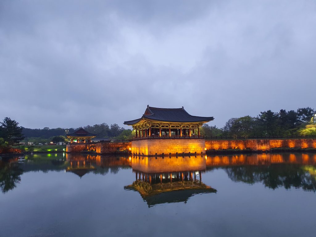 Why we stayed overnight, and why you should too
Gyeongju absolutely works as a day trip from Busan, but having stayed overnight ourselves, I'd genuinely recommend it if you can manage the extra night. The evening light at Wolji Pond, the quieter, almost meditative morning atmosphere at Tumuli Park before the tour groups descend, these are experiences that simply require being there outside standard day-trip hours. Trying to fit Bulguksa, Seokguram, and the town centre sights into a single rushed day from Busan does the whole place a disservice.
Where to stay in Gyeongju
Gyeongju's accommodation generally clusters into a few distinct areas.
Old Town / Hwangnidan-gil area — The best base if it's your first visit and you want everything within walking distance: the tomb complex, Cheomseongdae, and Wolji Pond are all close by. This area has fewer big hotel brands than other Korean cities, so options can sell out, book early, especially around cherry blossom season (late March to mid-April) or autumn foliage (mid to late October).
For a genuinely memorable stay, consider a hanok, a traditional Korean guesthouse. Hwangnamgwan, sitting at the end of Hwangnidan-gil, is the largest hanok property in Old Town, built around a koi pond with a beautifully lit courtyard at night, and includes a free hanbok experience for guests. Siwoowadang, right in the heart of the hanok village, is another well-reviewed option, known for warm, family-run hospitality and genuinely high-quality rooms for the style. [Browse hanok stays in Gyeongju →]
One practical note if you go the hanok route: traditional Korean sleeping is on floor mats over heated ondol floors. Many hanoks now offer Western beds too, but not all do, worth checking the listing carefully if that matters to you.
Near Gyeongju Station / city centre — More conventional hotel options if a hanok isn't for you. Commodore Hotel Gyeongju is a reliable, well-located mid-range choice. [Browse hotels in central Gyeongju →]
Bomun Lake area — Gyeongju's resort cluster, roughly 4km from the historic centre, built around a lake with mountain views, golf courses and bigger hotel infrastructure. Hilton Gyeongju is particularly well-reviewed for families, with a kids' pool and babysitting services. Good if you want resort comforts alongside the history, though it's a short taxi or bus ride from the main sights rather than walking distance.
Near Bulguksa Temple — A quieter option if you'd rather wake up close to the temple itself, ideal for a slower, more reflective pace. Several properties here also offer seasonal temple stay programmes if you want a deeper cultural experience.